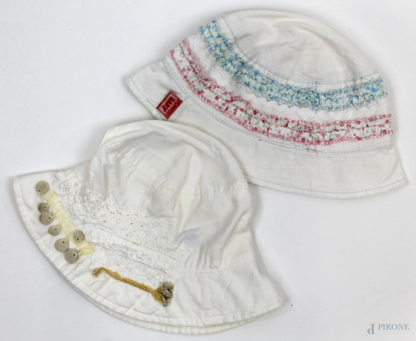 Lotto di due cappellini bianchi da bambina Gusella e Flowers Baby, con ricami e applicazioni.