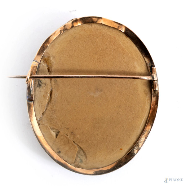 Spilla in oro con centrale in pietra lavica e rilievo di putto, cm 4,5x3,5, peso complessivo lord...