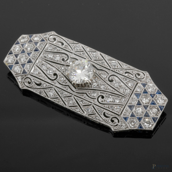Spilla ottagonale in oro bianco finemente lavorato con pavè brillanti e zaffiri e diamantre centrale taglio brillante (mm 7,3), gr. 8,6