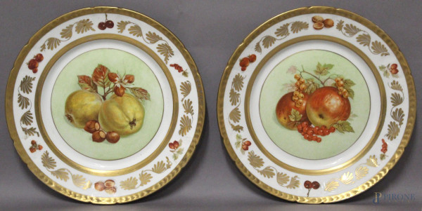 Coppia di piatti in porcellana a decoro di mele con fasce e bordi dorati, primi Novecento, diametro 25 cm.