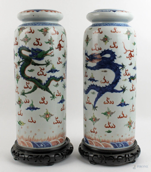 Coppia di vasi cilindrici in porcellana dipinta con decoro di dragoni, altezza cm. 35, poggianti su basi in legno, Cina, XX secolo.