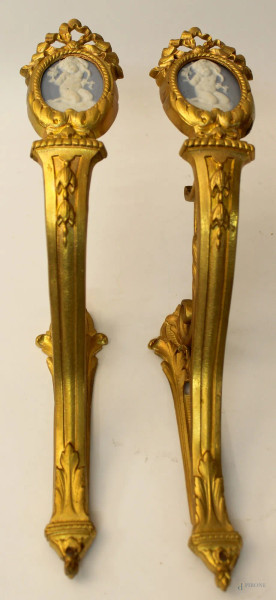 Coppia di reggitende in bronzo cesellato e dorato con placche in porcellana Wedgwood a soggetti di fanciulli, cm 34 x 19.