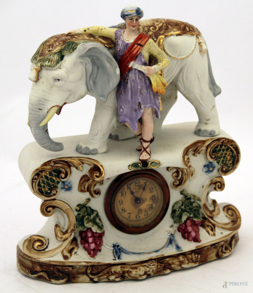 Orologio in bisquit policroma, sormontato da elefante con figura, base con orologio , finiture dorate, primi 900, (mancanze), h. 25 cm
