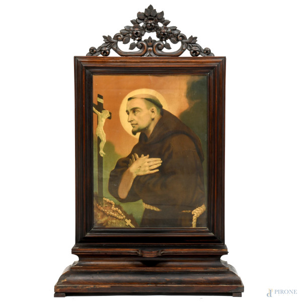 Cornice da terra in legno intagliato con elemento apicale a volute contenente stampa oleografica raffigurante San Francesco in meditazione, XX secolo, misure complessive cm 119x77x18, luce cm 64,5x49,5, (segni di usura, scalfiture, rotture, difetti, fori di tarlo)