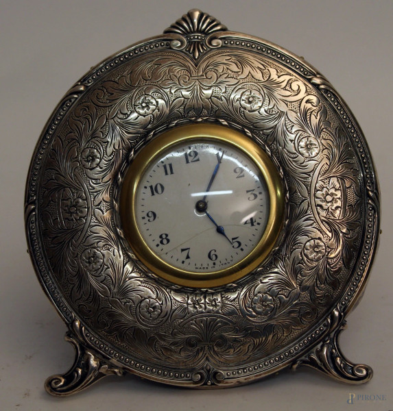 Orologio sveglia da tavolo, rivestito in argento cesellato, diametro 15 cm.