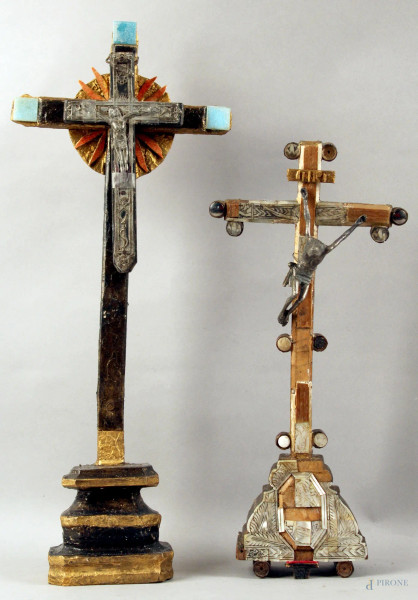 Lotto composto da due crocifissi da tavolo in materiali ed epoche diverse, h. max 46,5 cm, (mancanze e difetti).