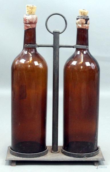Lotto di due grandi bottiglie con base in ferro, altezza cm. 56, inizi XX secolo.