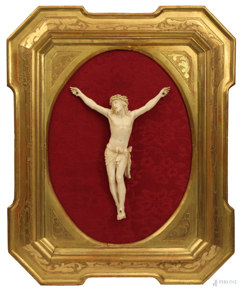 Cristo in avorio del XIX sec., h. cm 30, entro cornice dorata.