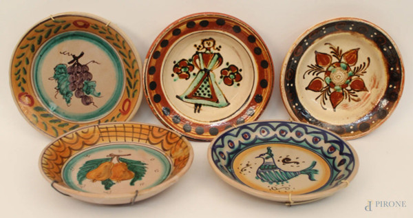 Lotto composto da cinque piatti diversi in maiolica a decoro di frutta, figura ed animali, diametro 24 cm.