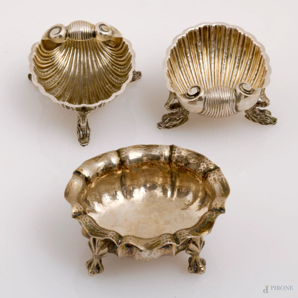 Lotto di tre salierine in argento 800/000, due a guisa di conchiglia poggiante su tre piedini a foggia di delfino e una a orlo mistilineo poggianti su piedini ferini, XX secolo, misure massime cm 3,5x7,5x6,5, peso complessivo gr 160, (difetti)