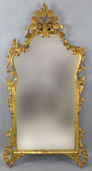 Specchiera di linea sagomata in legno dorato ed intagliato a tralci e volute, altezza cm. 133x72, XX secolo