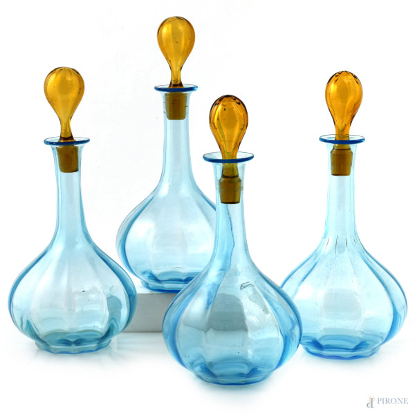 Lotto di quattro bottiglie in vetro nei toni dell'azzurro e del giallo, XX secolo, altezza cm 22, (tappi non pertinenti, segni di usura, graffi, sbeccature)