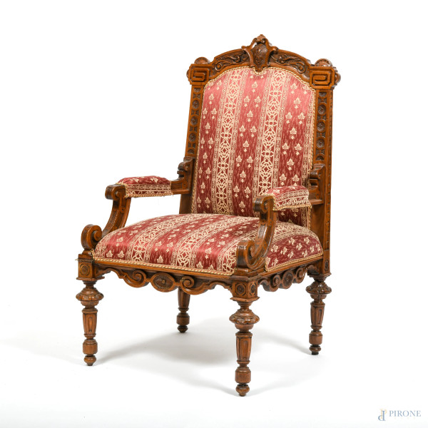 Poltrona in noce intagliato con seduta e schienale imbottiti e rivestiti in tessuto color porpora e panna, XX secolo, cm 112x62,5x62,5, (segni di usura, scalfiture, fori di tarlo)