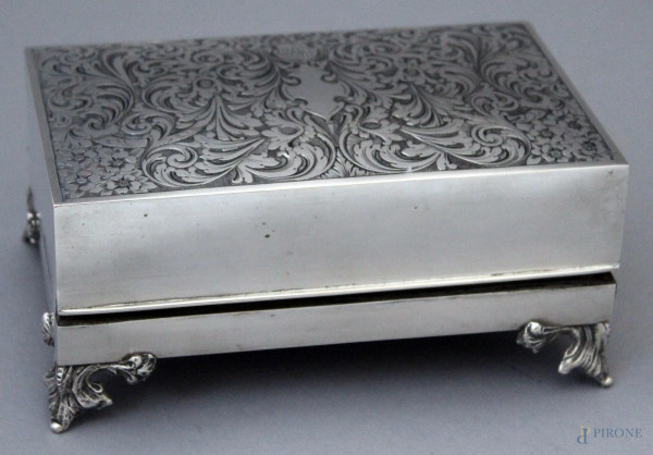 Cofanetto rivestito in argento inciso e cesellato, poggiante su quattro piedini, h. 8,5x18,5x12 cm.