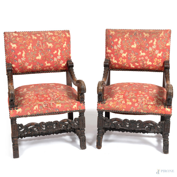 Coppia di poltrone con struttura in legno intagliato e seduta e schienale imbottiti e rivestiti in tessuto nei toni del rosso, verde e panna con decori animali e vegetali, XX secolo, cm 100x63x66 circa, (segni di usura, scalfiture, difetti, lacerazioni, consunzioni)