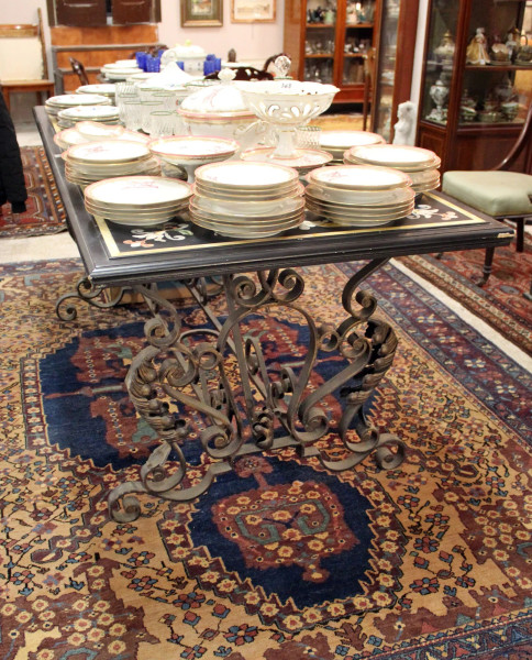 Tavolo di linea rettangolare con piano in legno dipinto a decoro floreale su fondo ebanizzato, poggiante su base in ferro