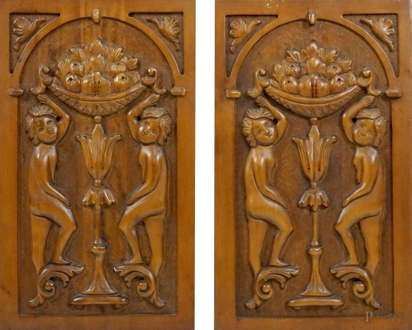 Lotto di due pannelli in legno intagliato e scolpito a rilievo, cm 56,5x32,5x2, XX secolo, (difetti).