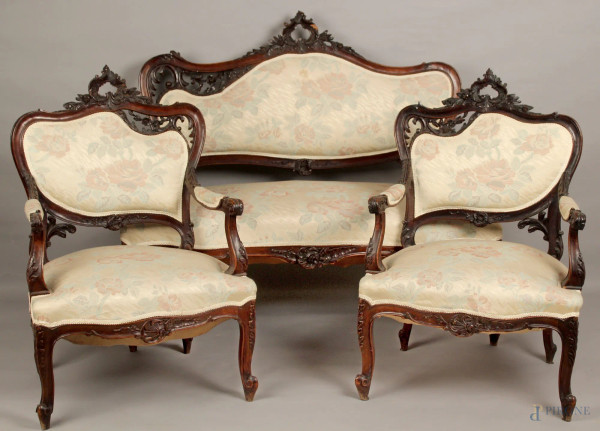 Salotto composto da divano e due poltrone in noce, particolari intagliati, rivestito in stoffa fiorata, periodo Liberty.