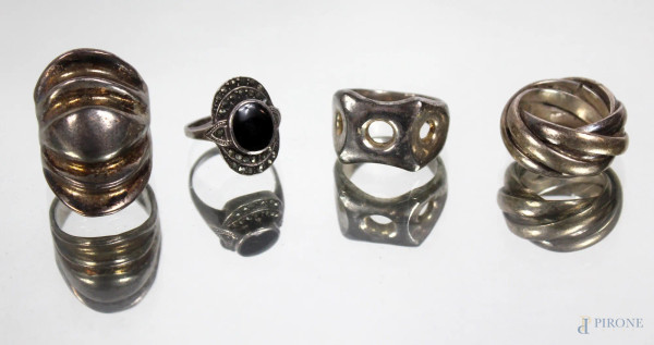 Lotto di quattro anelli in metallo argentato, forme e misure diverse.