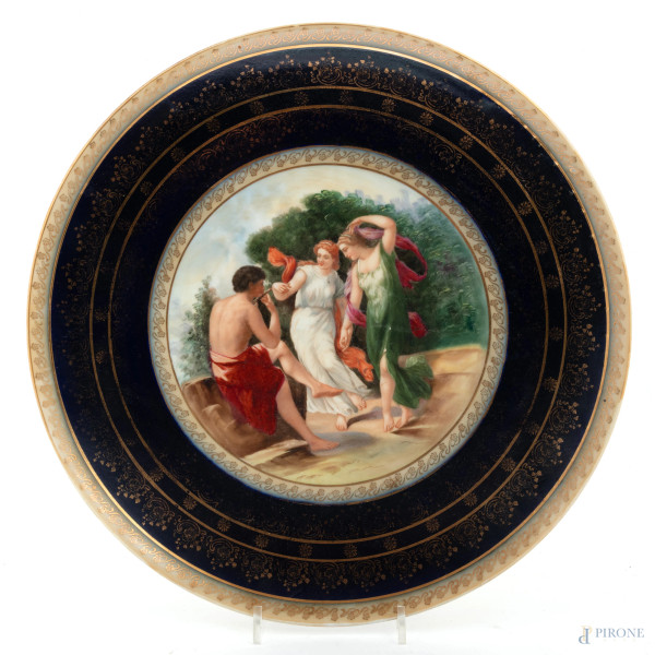 Piatto in porcellana policroma Vecchia Vienna con orlo nei toni dell'oro e del blu con scena mitologica al cavetto, XIX-XX secolo, diametro cm 38, (segni di usura, scoloriture)