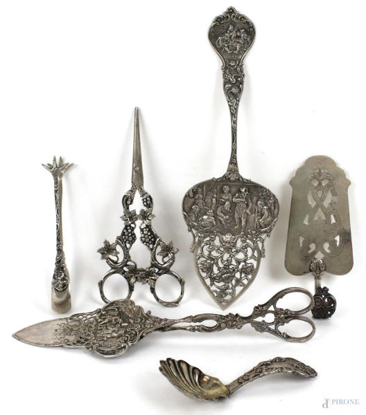 Lotto composto da una forbice, tre palette, un cucchiaio ed una pinza in argento lavorato, inizi XX secolo, gr 280