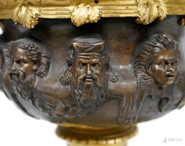 Coppa in bronzo patinato e dorato con pareti cesellate a sequenza di teste virili, due anse a ram...