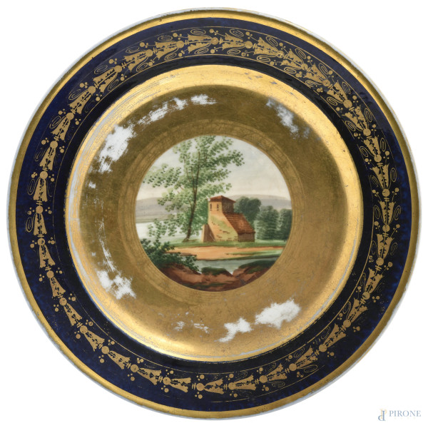 Piatto in porcellana con decori blu e oro e casolare al cavetto, XX secolo, cm 23, (segni di usura, difetti, cadute di doratura)