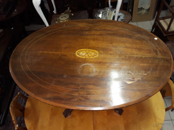 Tavolo di linea ovale in noce piano filettato poggiante su quattro gambe intagliate, h.72x115x84 cm.