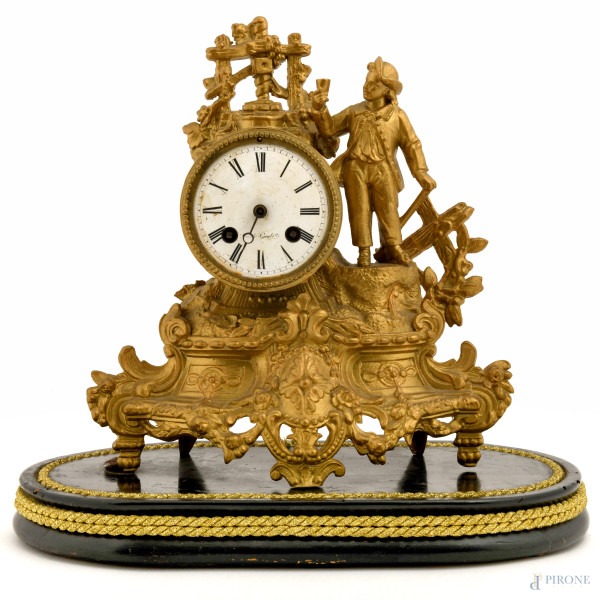 Pendola da tavolo in antimonio dorato con quadrante circolare e decori con figura maschile in atteggiamento conviviale, base in legno laccato, XX secolo, cm 32x34x18, (difetti, meccanismo da revisionare)