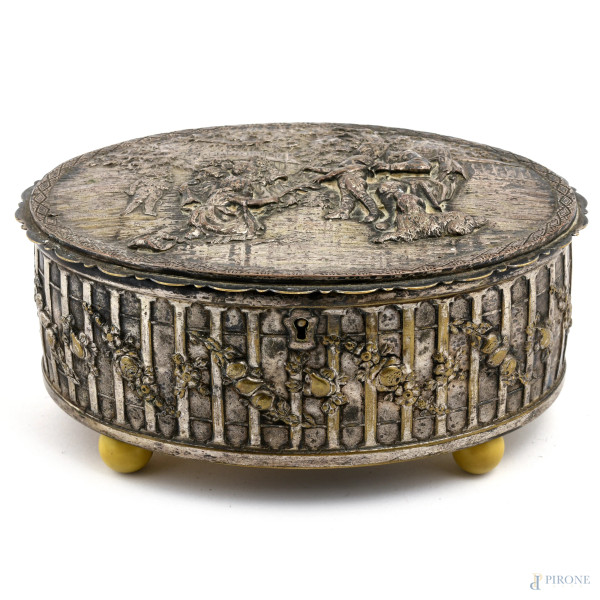 Scatola in metallo argentato riccamente cesellato al coperchio con scene di gioco tra bambini, XX secolo, cm 8,5x19x15, (segni di usura)