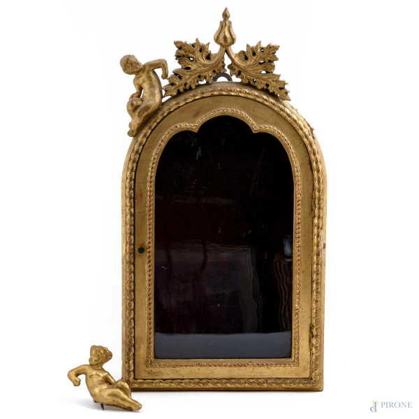 Cornice bacheca in legno dorato e intagliato con elemento apicale a guisa di putti affiancanti decorazioni fogliacee. Interno in velluto magenta, XX secolo, cm 53x28x13,5(segni di usura, putto da ricollocare)