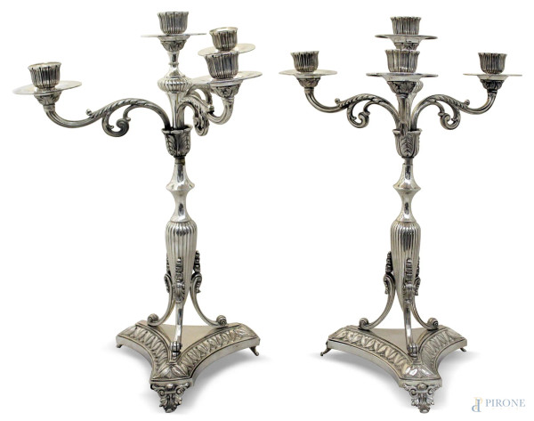 Coppia di candelieri a quattro luci in argento, poggianti su base e tre piedini, gr. 2520, h. 40 cm.