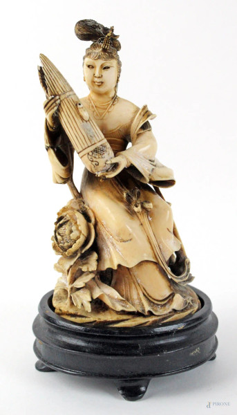 Gruppo scultoreo in avorio parzialmente dipinto raffigurante figura femminile che tiene tra le mani un flauto Sheng, altezza cm. 14, poggiante su base in legno, inizi XX secolo, marcato sotto la base.