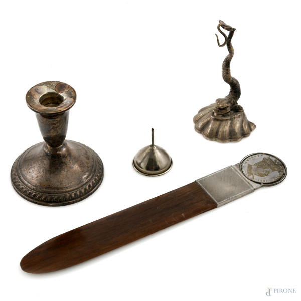 Lotto composto da un portaorologio  in argento a foggia di delfino, da un piccolo imbuto in argento, da un candeliere in argento sterling e da un tagliacarte in legno e argento 800 con medaglia al manico, XX secolo, lunghezza massima cm 27,5, peso lordo complessivo gr 410, (segni di usura)