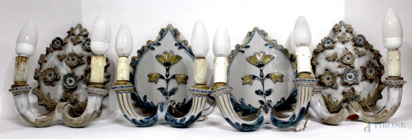 Lotto di due coppie di appliques a due luci in ceramica sbalzata, h. 23 cm.
