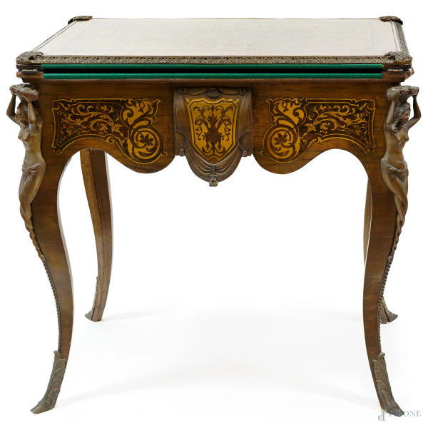 Tavolo da gioco in legno con intarsi Boulle ad arabeschi sui lati e sul piano rettangolare dal perimetro bronzeo cesellato, piano apribile foderato in velluto verde, cariatidi bronzee agli angoli, cm 76,5x78,5x52 (aperto: 103x78,5), XIX secolo, difetti.