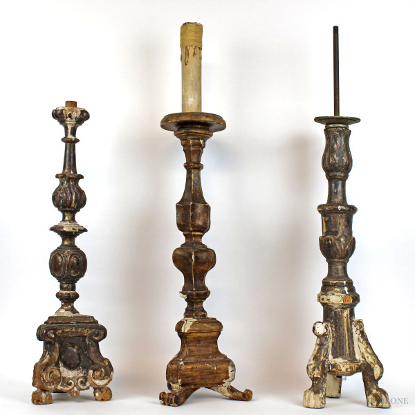 Lotto di tre candelieri in legno intagliato e dorato poggianti su basi a tripode, epoche diverse, alt. max cm 70, (difetti).