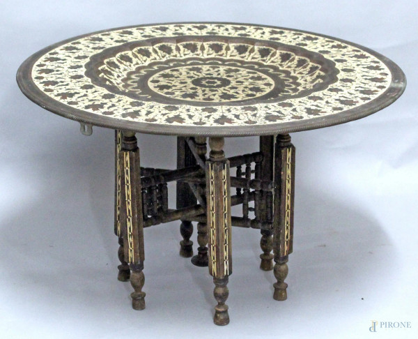 Tavolino da salotto, piano in metallo, poggiante su base in legno, arte orientale, H. 48, diametro 77 cm.
