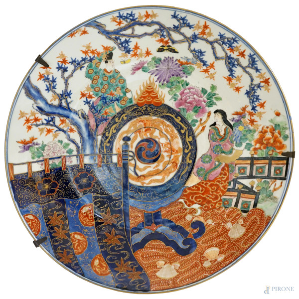 Grande piatto in porcellana policroma con decoro di fiori e  personaggi di corte, diam.cm 41, Giappone, XX secolo.