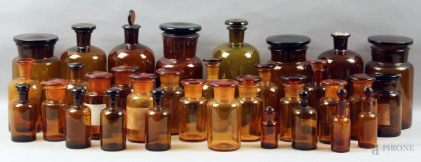 Lotto composto da trentatre contenitori da farmacia in vetro color ambra, h. max 24 cm, (piccoli difetti).