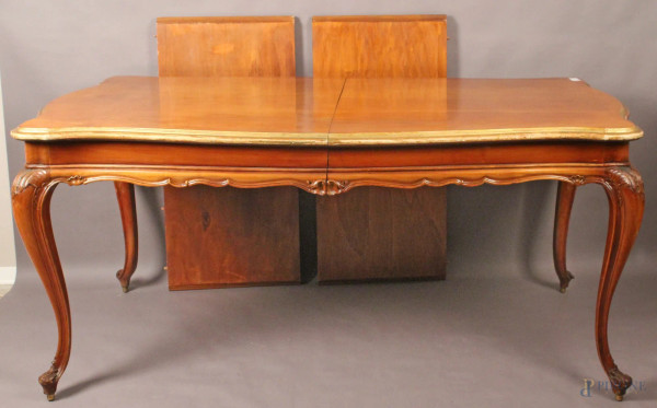 Tavolo di linea rettangolare in noce con particolari dorati, poggiante su quattro gambe mosse completo di due prolunghe da 50 cm, altezza 80x180x100 cm, XX secolo.