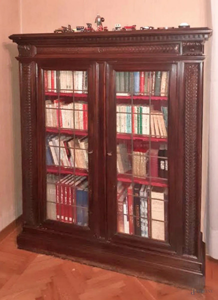 Piccola libreria in stile Rinascimento, in legno tinto a noce, a due sportelli a vetri piombati, particolari intagliati, altezza cm. 165x130x40, iniz XX secolo.