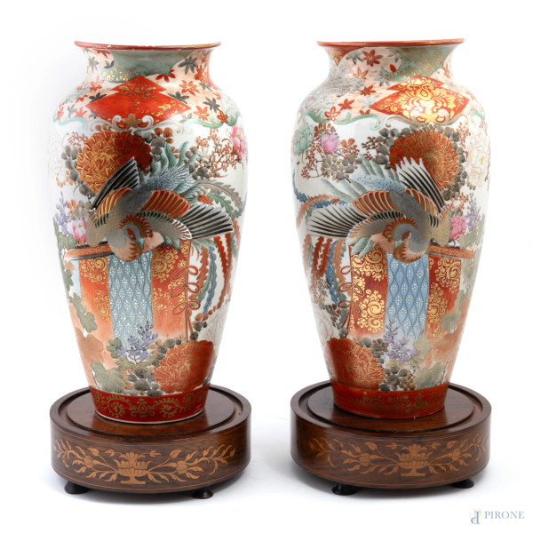Coppia di vasi in porcellana policroma decorati a motivi floreali e volatili su basi in legno, XX secolo, altezza cm 38, (segni di usura, felature, difetti).