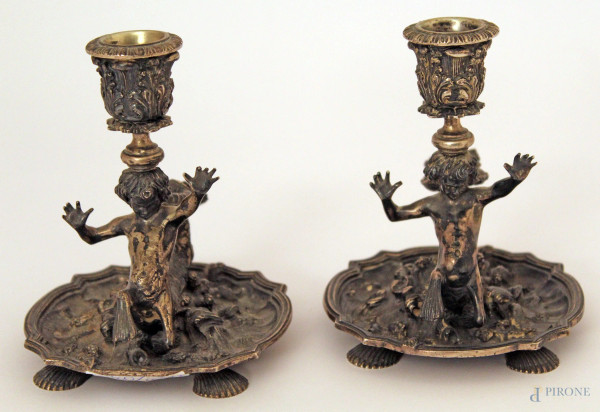 Coppia di candelieri ad una luce in argento cesellato, retti da tritoni, primi 900, h 13 cm