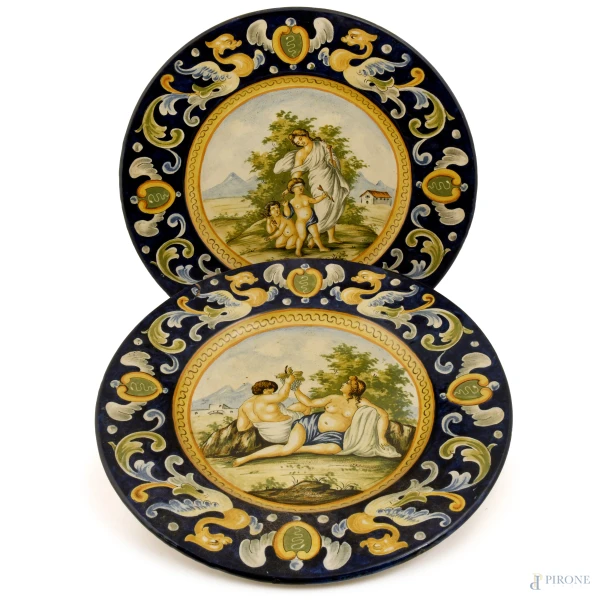 Coppia di grandi piatti decorativi raffiguranti nel cavetto scene di ispirazione mitologica in ambiente agreste, diametro cm 47, XX secolo, (difetti)