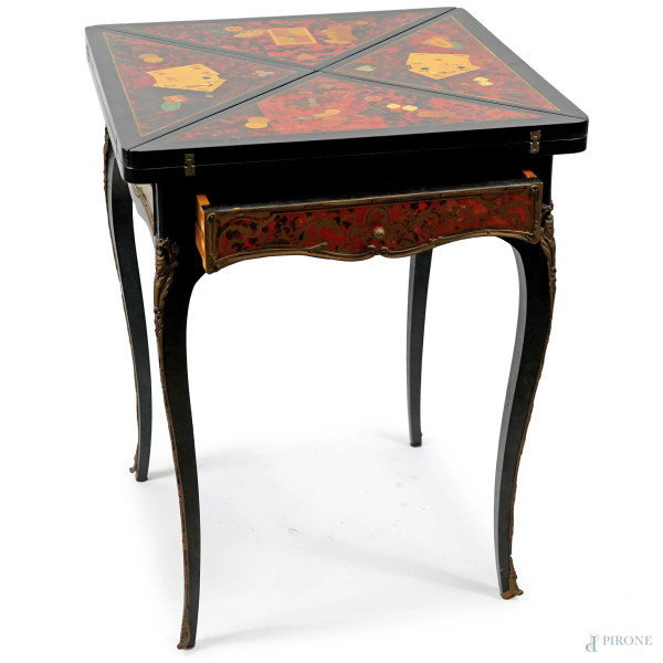 Tavolino a fazzoletto in stile Boulle in finta tartaruga e metallo dorato, piano intarsiato in varie essenze rappresentanti carte da gioco e pedine, aperto presenta sul piano una scacchiera, XX secolo, cm 76x60x60, aperto cm 76x85x85