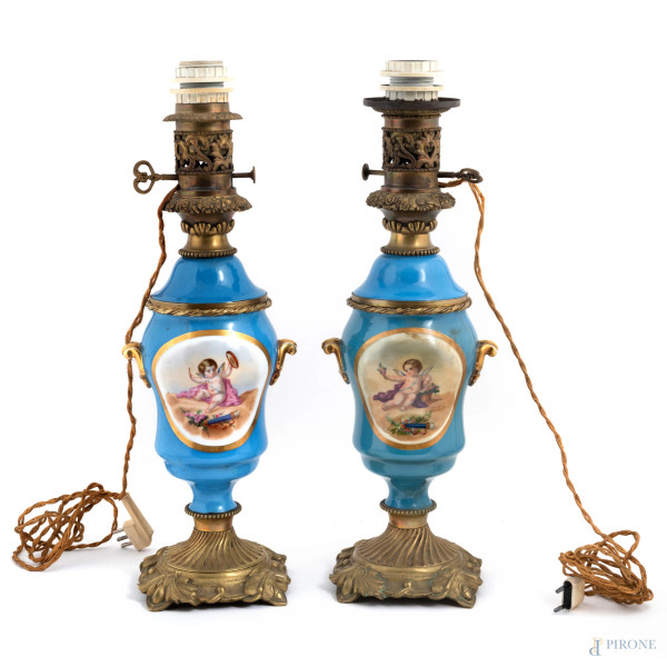 Lotto di due lampade in porcellana dipinta a fondo celeste con putti alati. Inserti in bronzo dorato. XX secolo, altezza cm 50, (da revisionare, segni di usura, difetti di cottura, cadute di smalto)