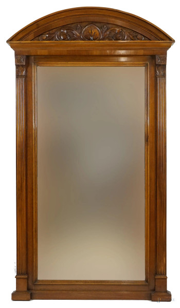 Specchiera in noce di linea sagomata, XX secolo, cimasa intagliata a motivi fogliacei, laterali a paraste scanalate, cm h 173x99x11,5, (difetti).
