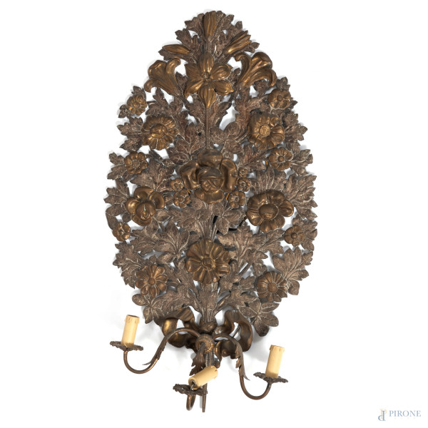Applique a tre luci in lamina di metallo cesellato a volute vegetali e fiori, XX secolo, altezza cm 80,5, (segni di usura, difetti, da revisionare)