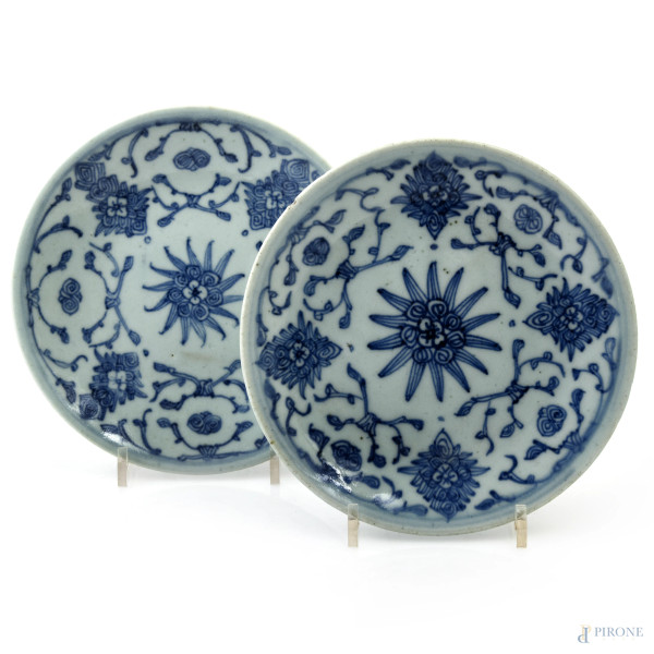 Lotto di due piattini in ceramica  con decori nei toni del bianco e del blu a volute, diametro cm 18. Cina, XX secolo, (segni di usura, scalfiture, difetti di cottura)